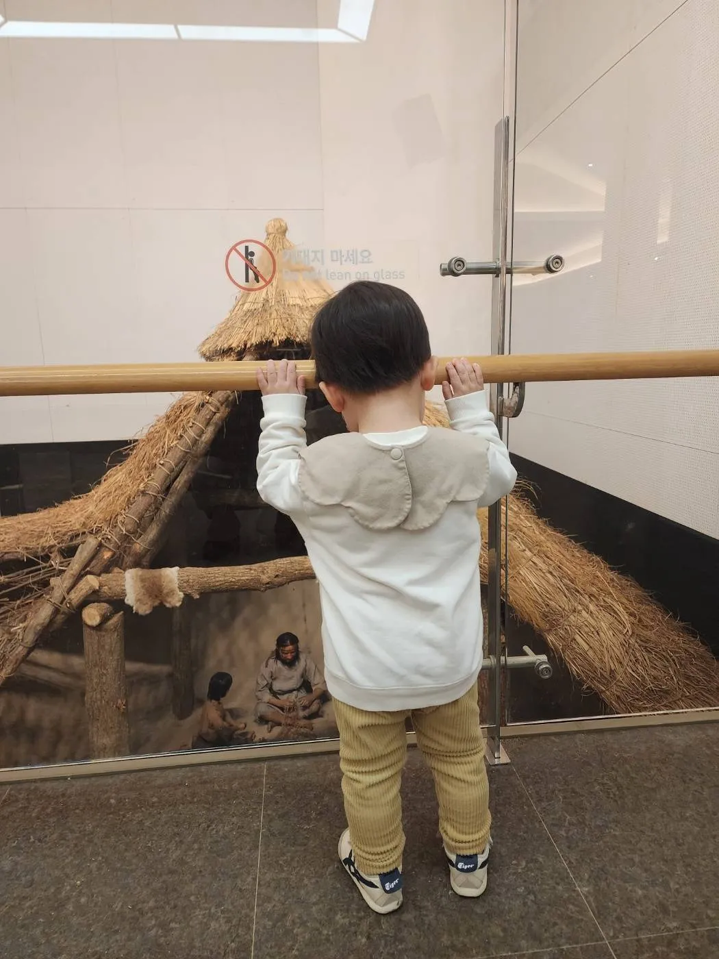 움집 모형을 구경하는 아이