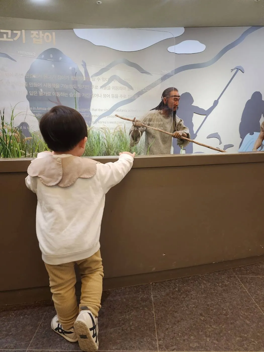 선사시대 사람 모형을 바라보는 아이